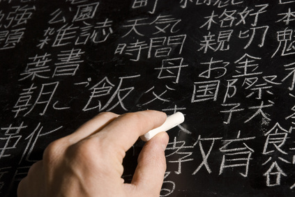 Mann schreibt mehrere japanische und chinesische Zeichen an eine Tafel